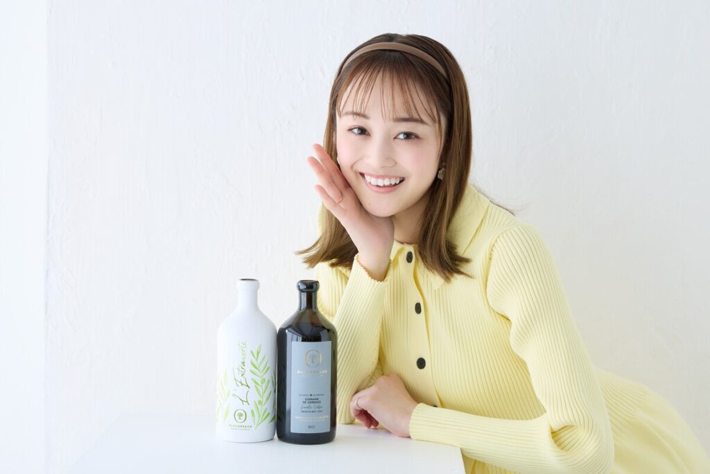 オリーブオイルの瓶2本と、黄色の洋服を着た元タカラジェンヌの舞空瞳さん