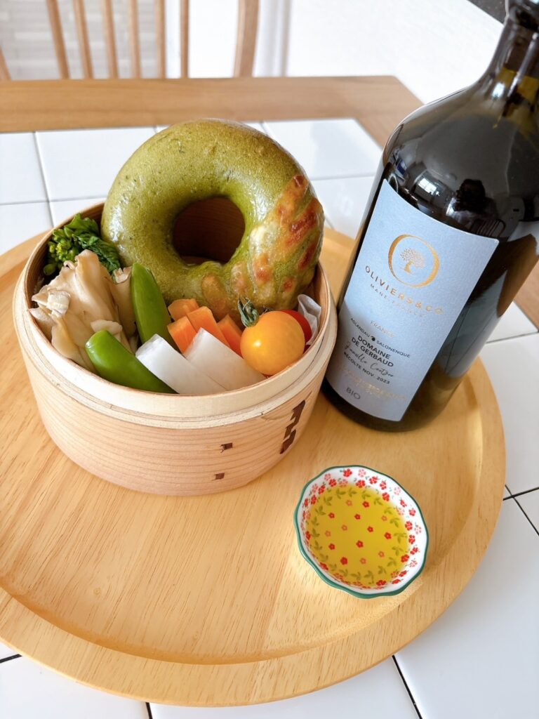 せいろに野菜とベーグルを入れ、そばにオリーブオイルを置いた写真。