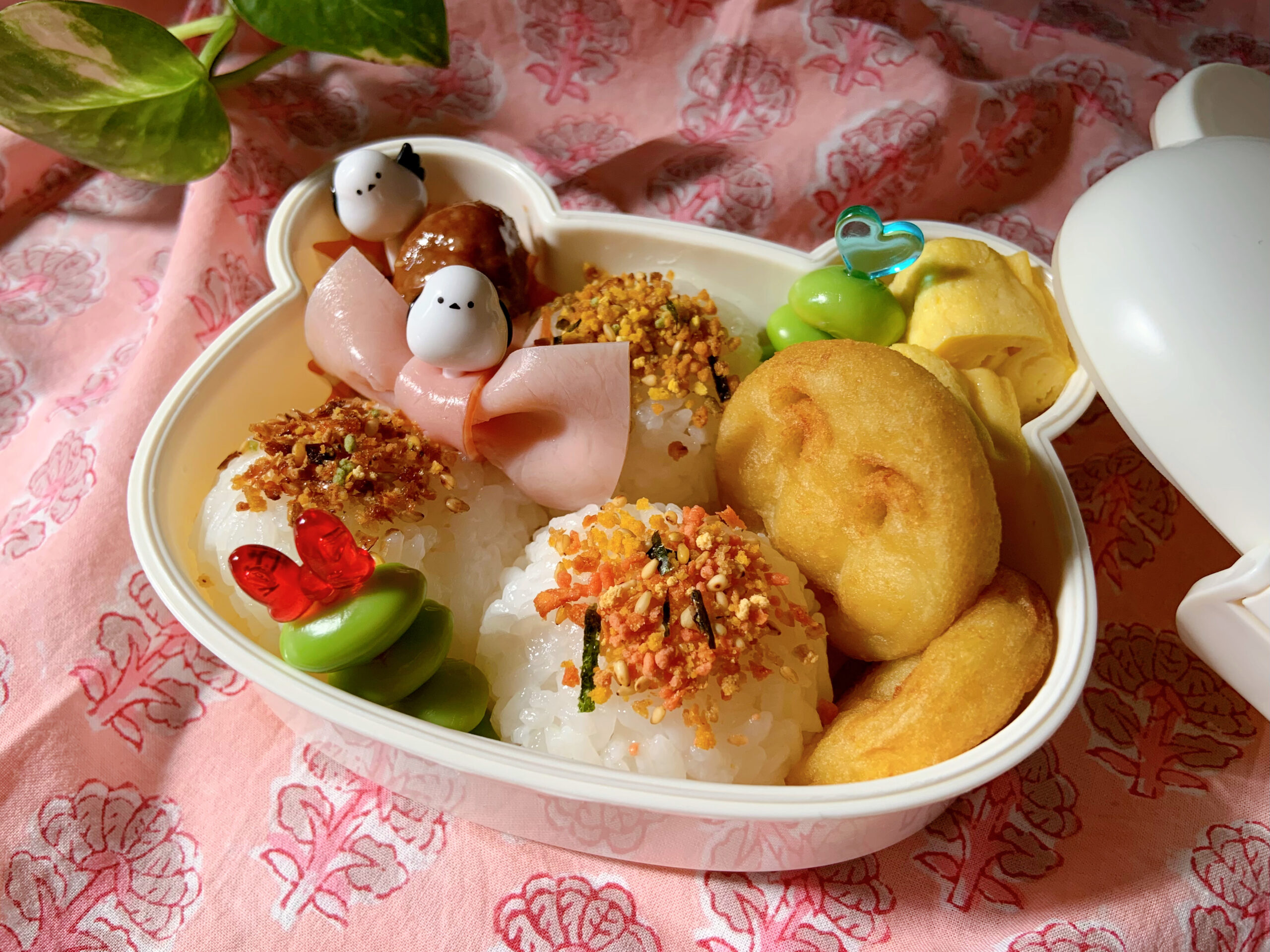 幼稚園に通う子供のお弁当。おにぎり、ミートボール、卵焼き、アンパンマンポテト、枝豆、ハムリボン。