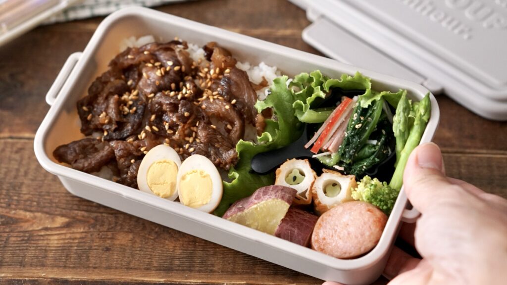 牛肉のしぐれ煮をのせたお弁当。カニカマと小松菜のおひたし、うずらの卵、ちくわ、ブロッコリー、ソーセージ、さつまいもが入った秋らしいお弁当。セリアの100円のお弁当箱が可愛い。秋色でスモーキーカラー、グレーベージュが素敵。