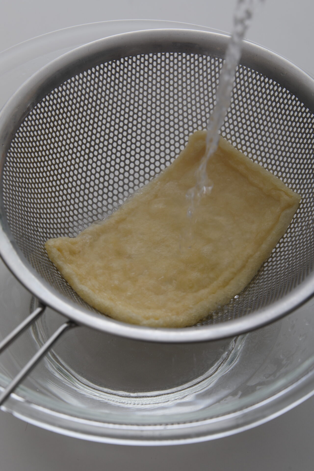 洗米して油揚げの油抜きをする