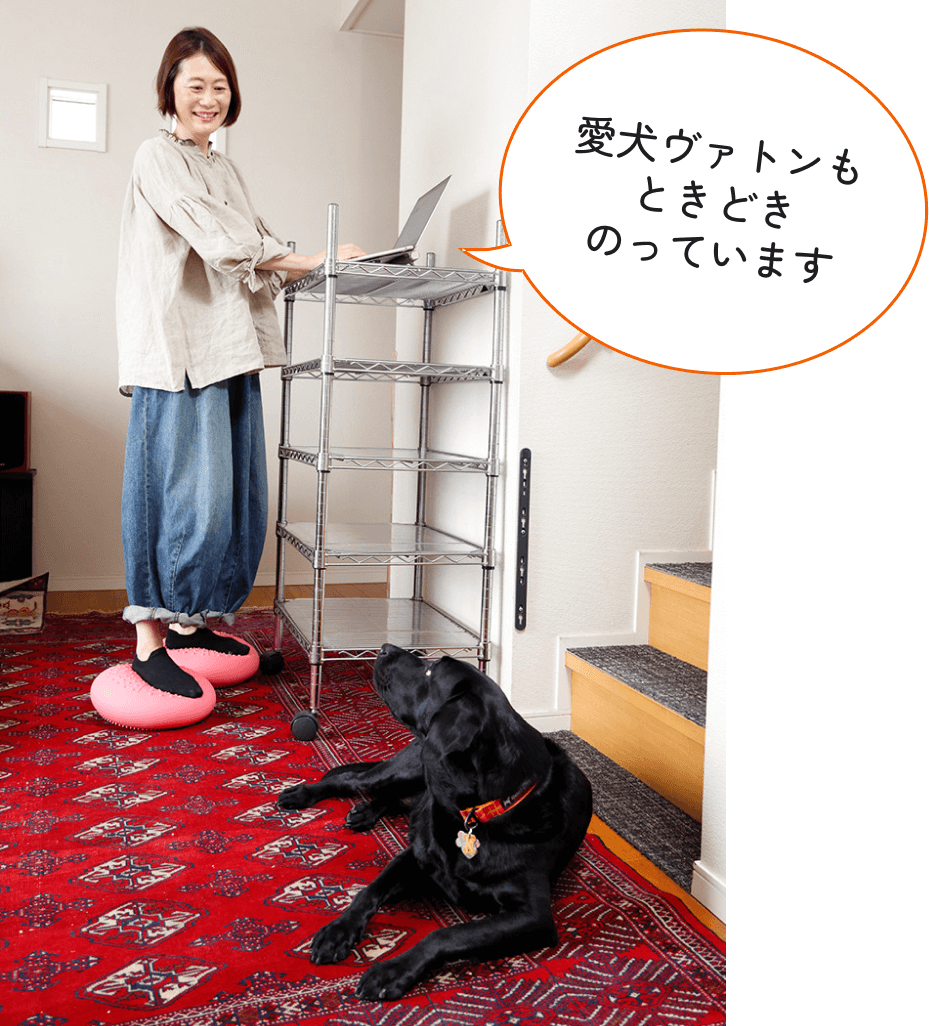 バランスボールにのってパソコン作業をするまさみさんと愛犬のヴァトン