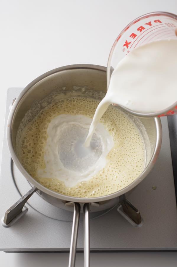 牛乳を一度に加えて中火にし、泡立て器で混ぜ合わせる