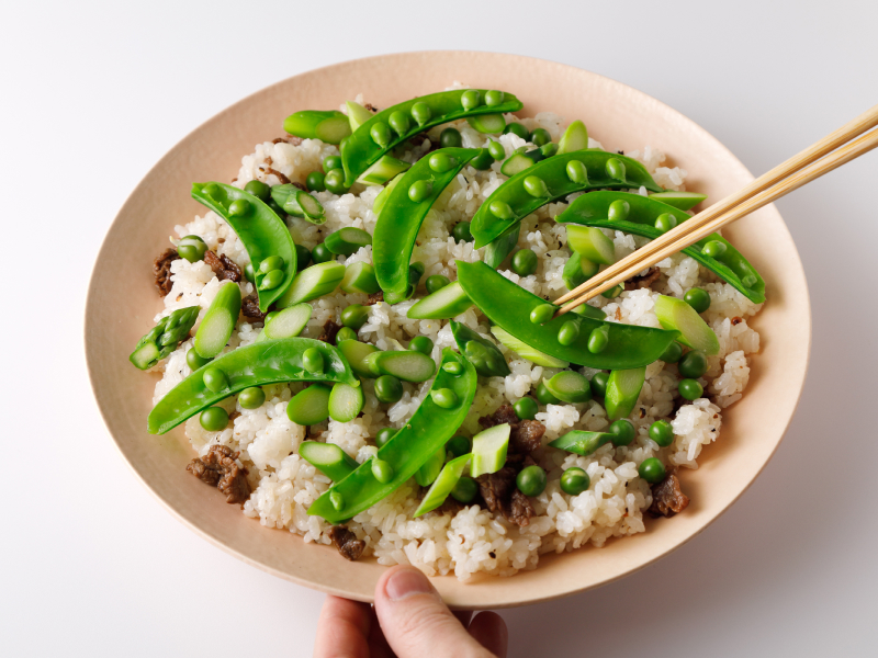 牛肉のしぐれ煮と緑鮮やかな麩で野菜を大皿に盛られたご飯の上に盛り付けている