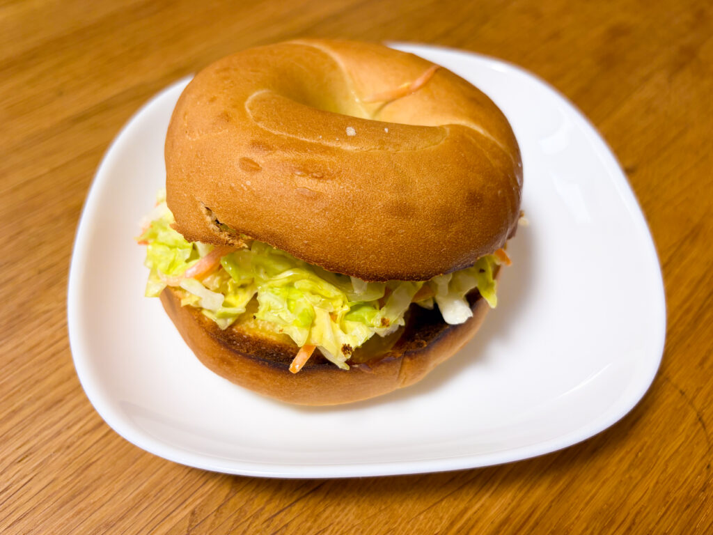 ベーグルでコールスローとチーズと卵焼きを挟んだサンドイッチ
